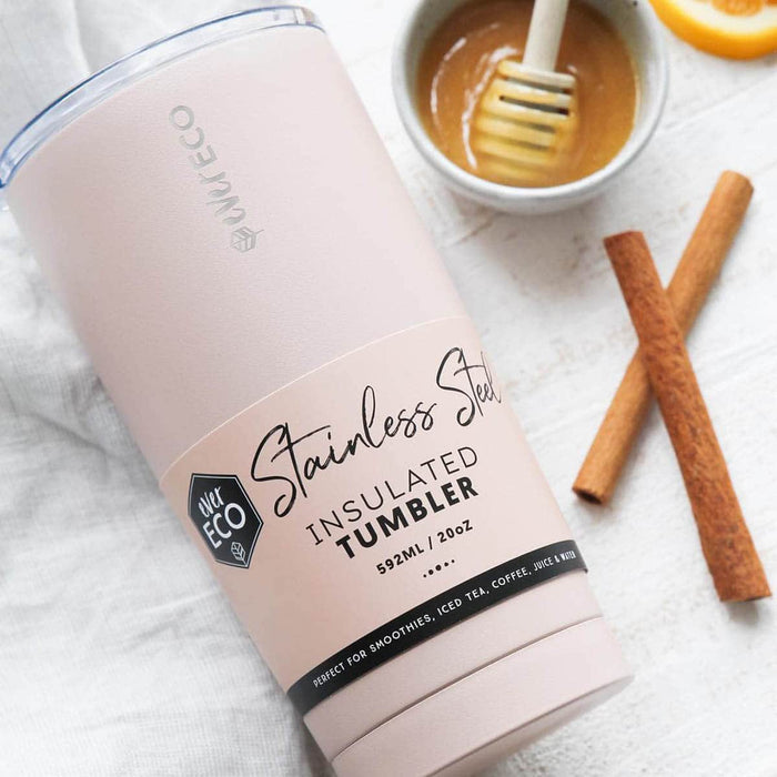 Stainless steel insulated tumbler on a white tea towel styled next to a couple of cinnamon sticks & honey in a bowl.