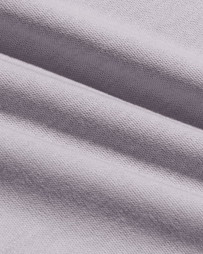 A close-up of draped light gray knit fabric with a fine ribbed texture and soft folds.