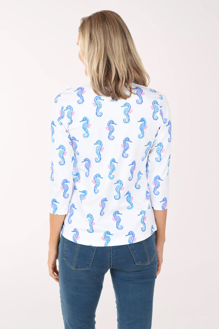 Woman wearing a white blouse with blue seahorse pattern on a white background
