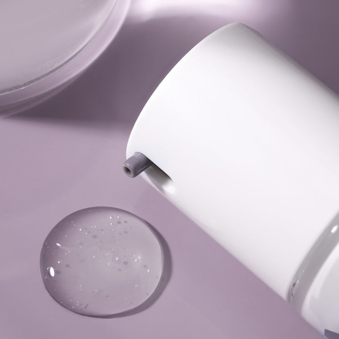 Close-up of Vibrant Scalp Treatment bottle applicator showing bristled spoolie and serum droplets on mauve background