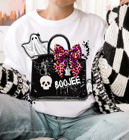 White short sleeve tee with a large playful Halloween graphic featuring a ghost, skull, colorful bow, and chic handbag.