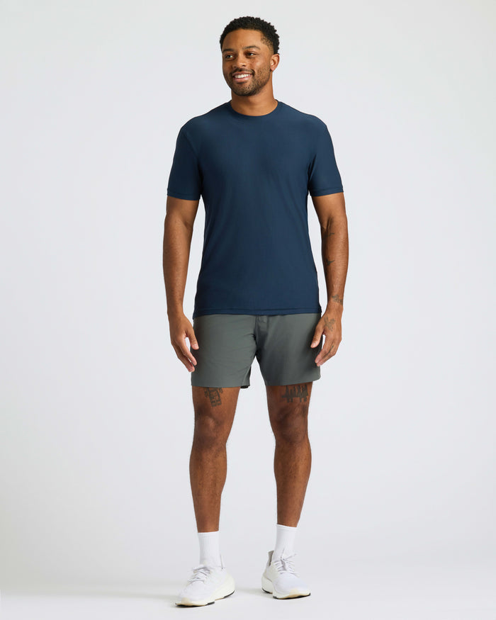Man wearing Navy Active Crew Neck Tee, gray shorts, and white sneakers.