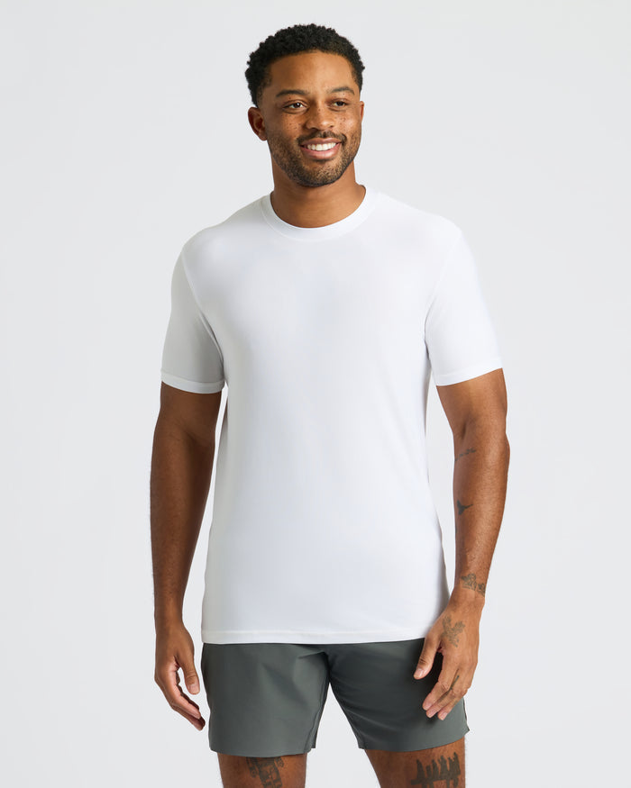 Man in White Active Crew Neck Tee and olive-gray shorts, smiling.
