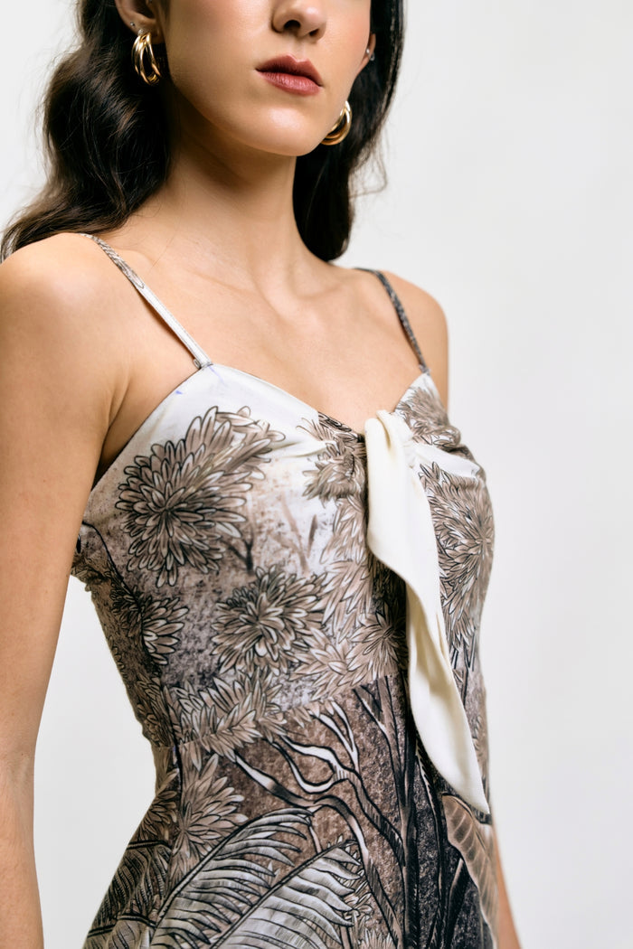 Model in Afterlight Dress with botanical print, layered fringe hem, beige boots, and gold jewelry