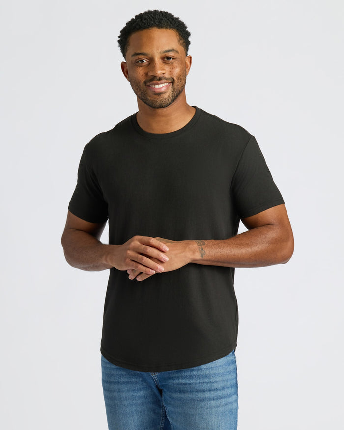Man wearing a black t-shirt and blue jeans on a white background