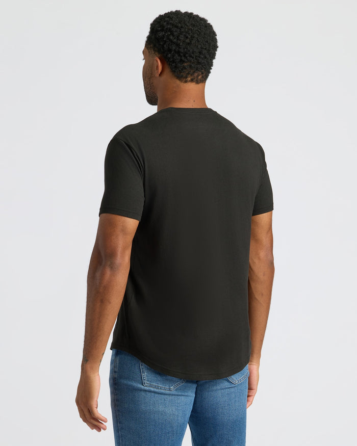 Man wearing a black t-shirt and blue jeans on a light gray background