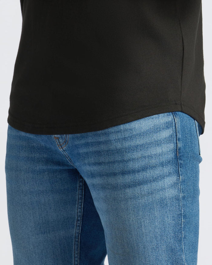 Person wearing a black shirt and blue jeans on a white background