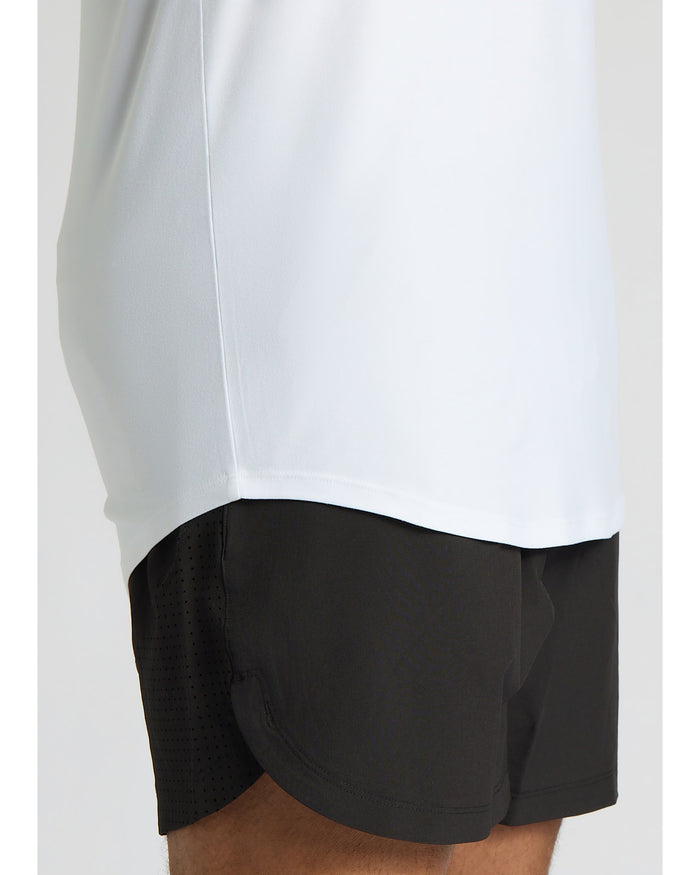 Person wearing a white long-sleeve shirt and black shorts on a light gray background