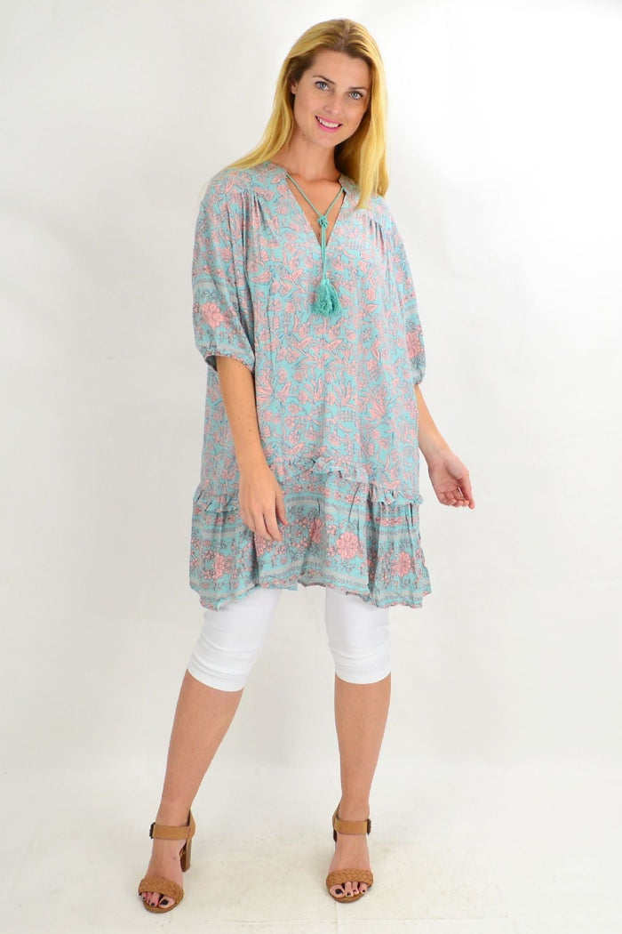 Aqua blue Style Fashion ruffle tunic top with flowing fabric and decorative ruffles, displayed on a hanger.