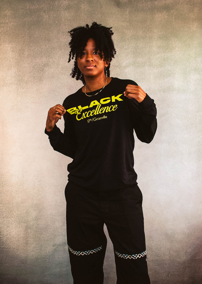 Person wearing a black sweatshirt with 'Black Excellence' text on a textured background