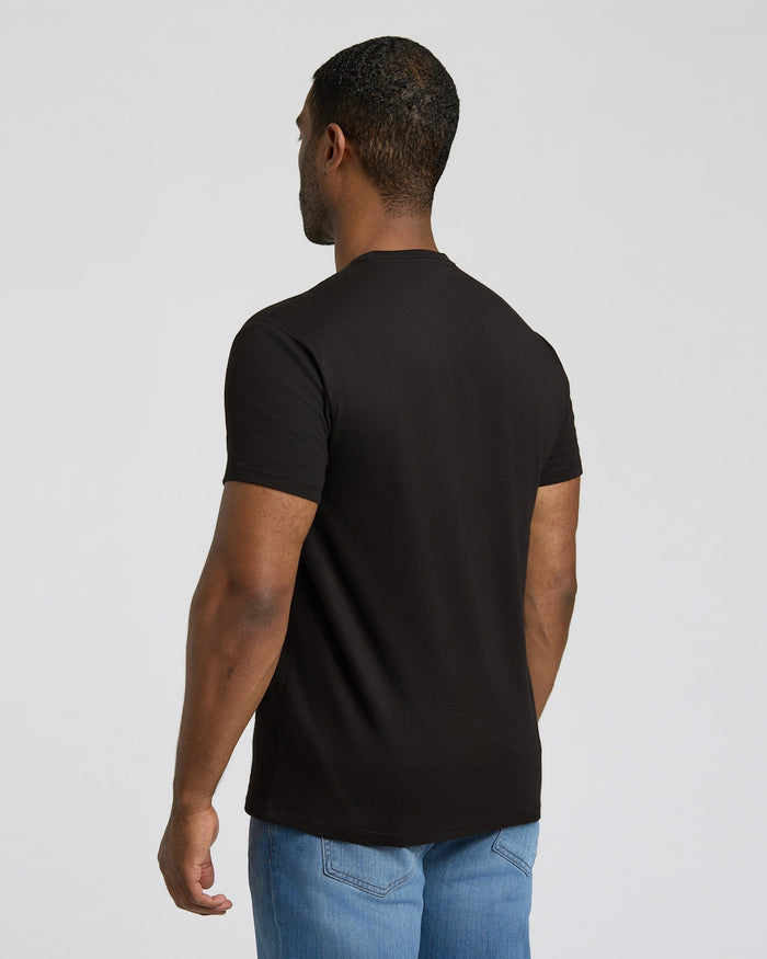 Man wearing a black t-shirt and blue jeans on a light gray background