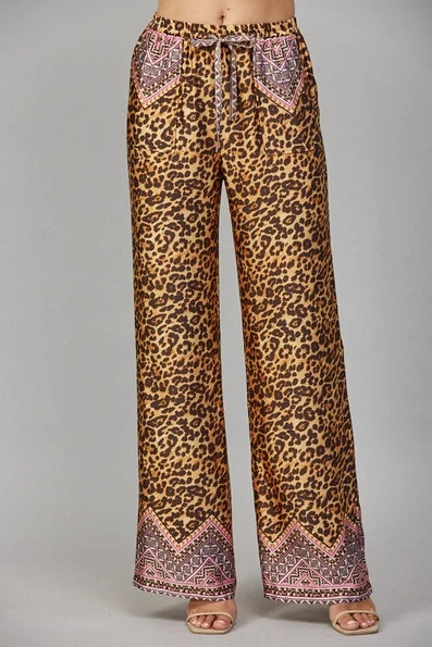 Brown wide leg pants with an animal motif border print at the pockets and hem, a drawstring waist, and a relaxed full-length silhouette.