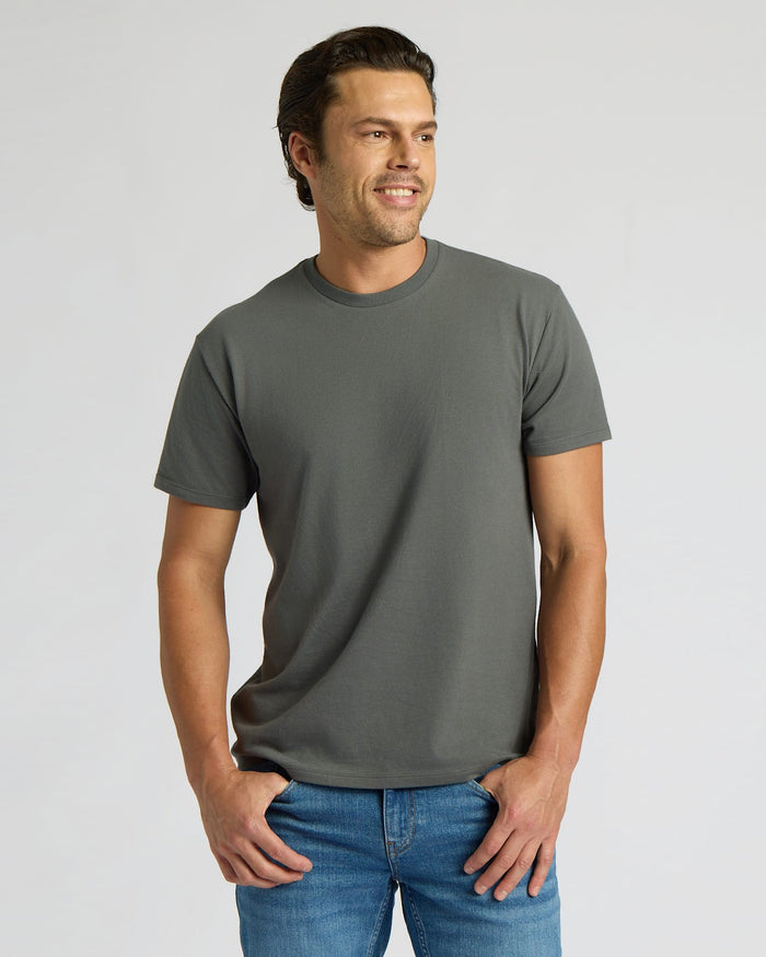 Man wearing a gray t-shirt and blue jeans on a light gray background