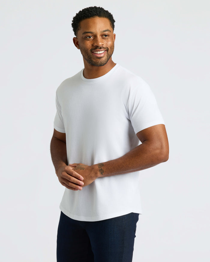 Man wearing All White Curved Hem Classic Crew Neck T-shirt, smiling.