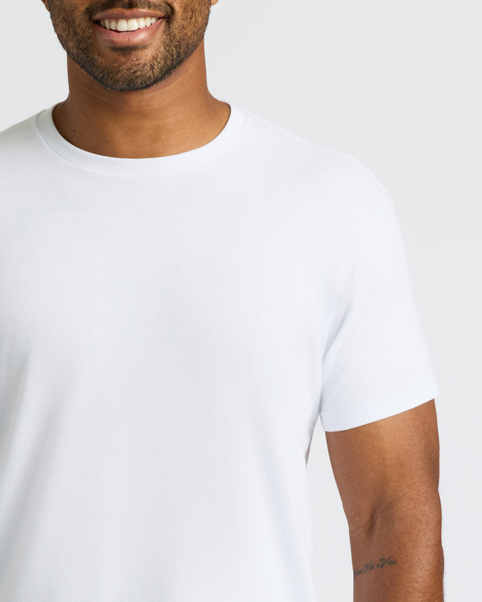 Man wearing All White Curved Hem Classic Crew Neck T-shirt, smiling.