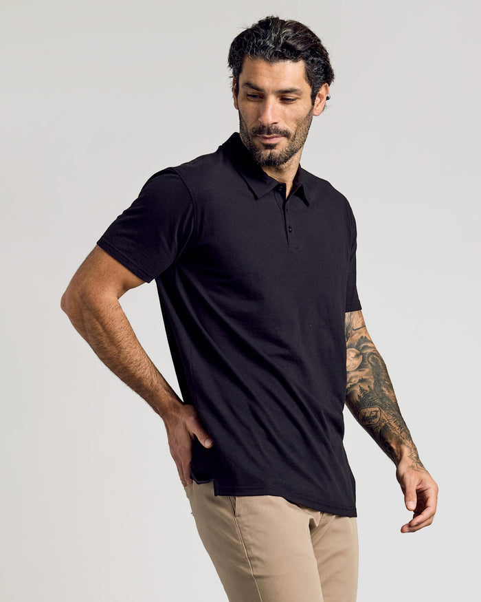 Man modeling Black Classic Polo with khaki pants, showcasing tattoos.