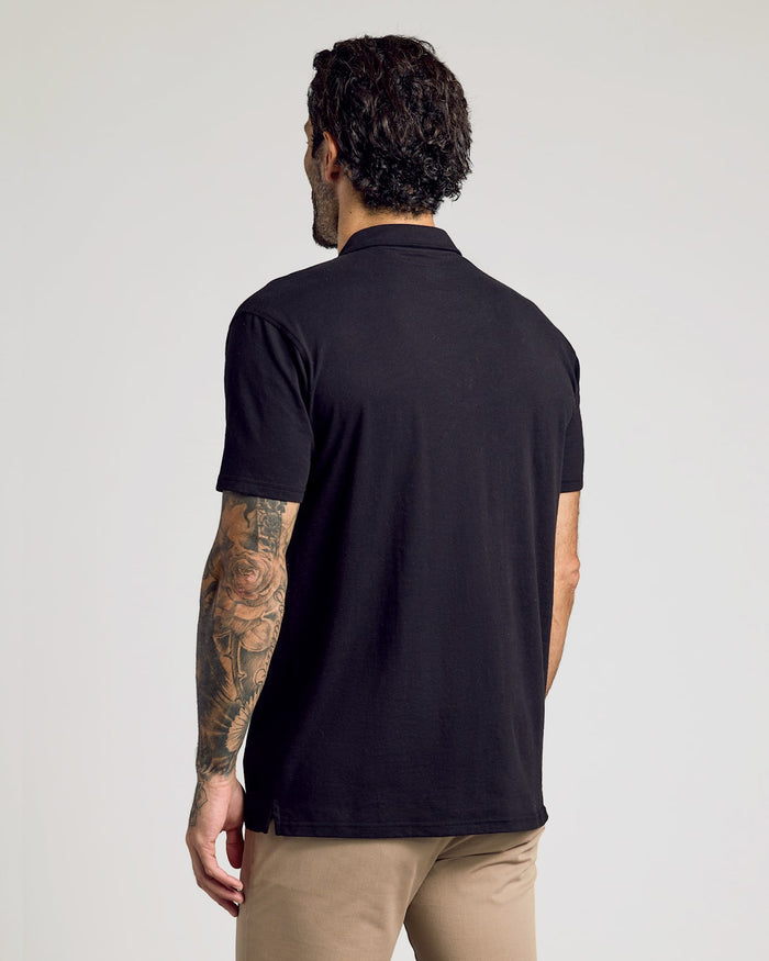 Man in Black Classic Polo with tattoos on left arm.