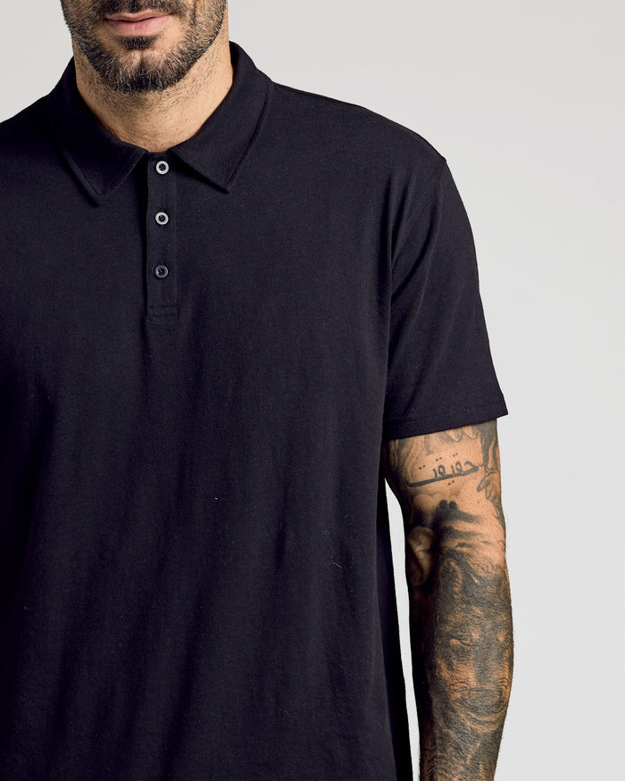 Man wearing Black Classic Polo with tattooed forearm visible.