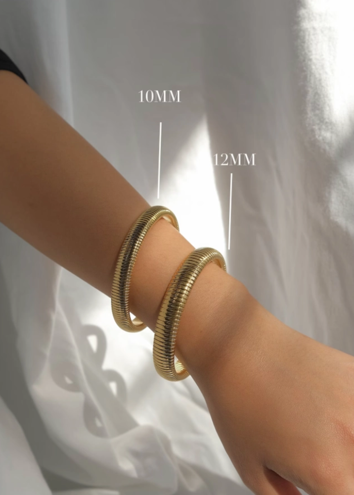 Woman wearing two gold bangle bracelets