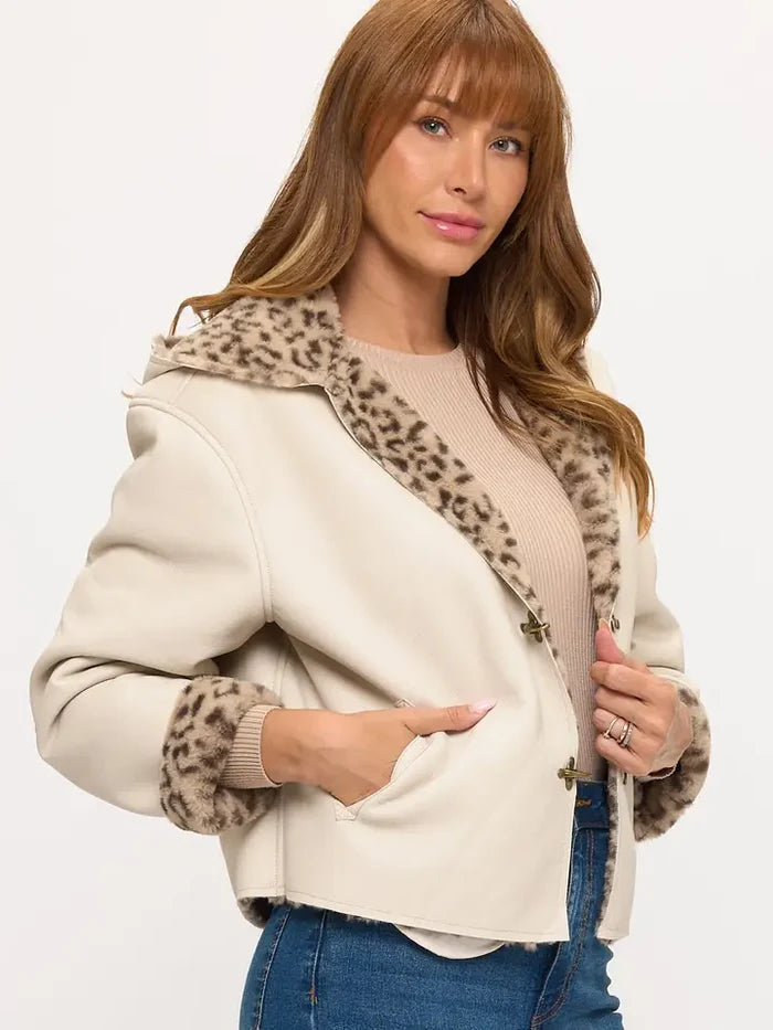 Cream cropped reversible jacket with toggle closures and leopard print lining visible at the collar and front opening.