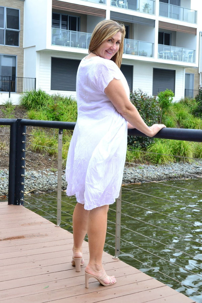 White cotton Sophia tunic dress by Wishstone displayed on a hanger, showcasing its simple, elegant design and crisp fabric.