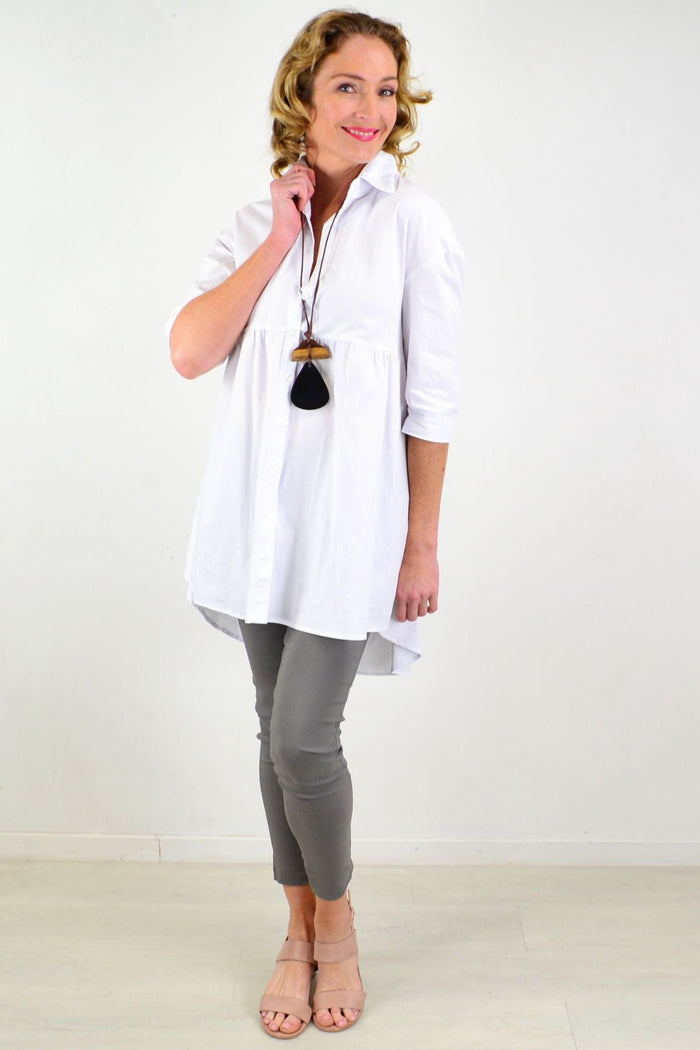 White trendsetting tunic shirt by Hourglass, featuring a relaxed fit and stylish design, displayed on a hanger.