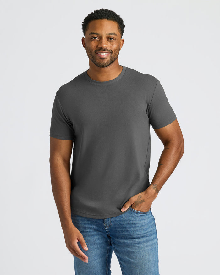 Man wearing a gray t-shirt and blue jeans on a light gray background