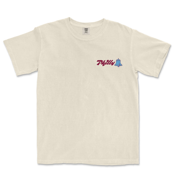 Cream-colored Comfort Colors tee featuring "Philly" text and a small blue bell graphic on the chest.