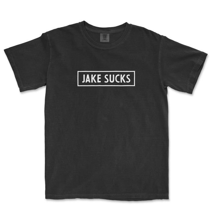 Black Comfort Colors® vintage t-shirt with "JAKE SUCKS" text inside a white rectangular border on the front.