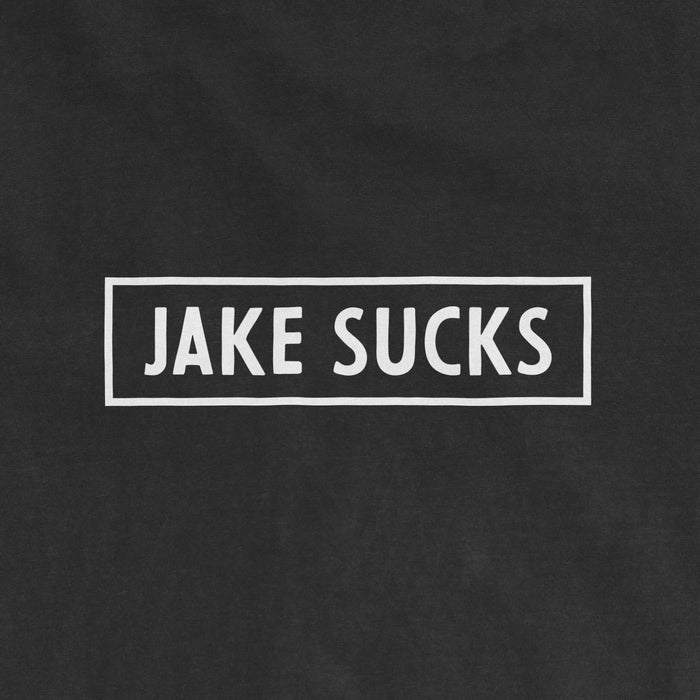 Black Comfort Colors® vintage tee with white rectangular outline and bold text that reads "JAKE SUCKS" in the center.