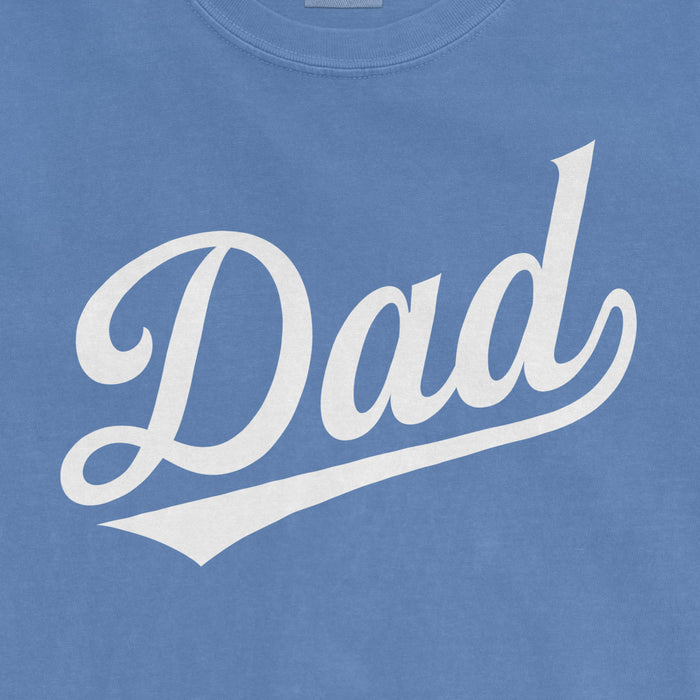 Light blue Comfort Colors T-shirt with white "Dad" text in a cursive font and a swooping underline.