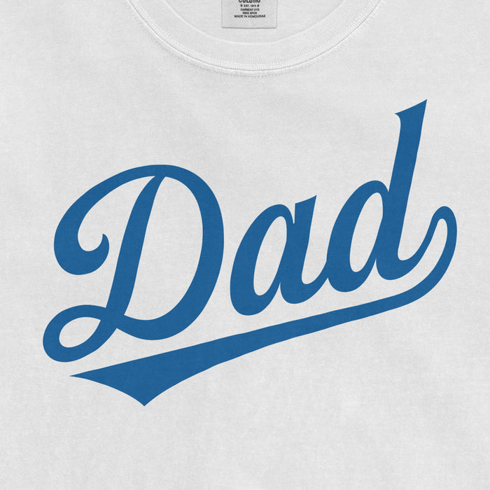 Close-up of a white Comfort Colors T-shirt with blue "Dad" text in a cursive font, celebrating baseball dad pride.