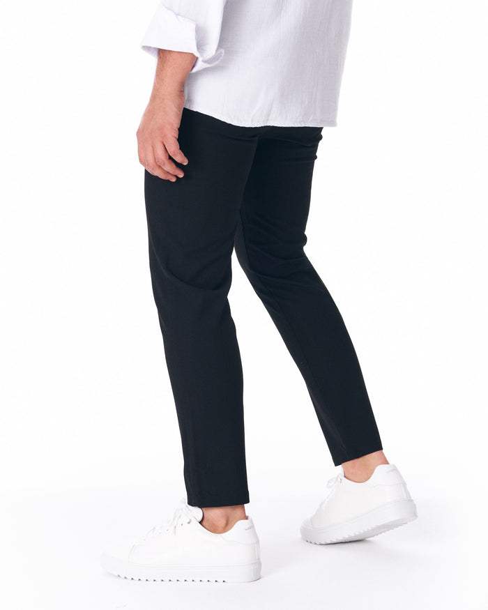 Martin Valen men's black lightweight trousers, side profile showing slim fit and cropped hem with sneakers