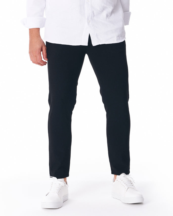 Martin Valen men's lightweight black trousers, front view on model, slim ankle-length fit shown with white sneakers