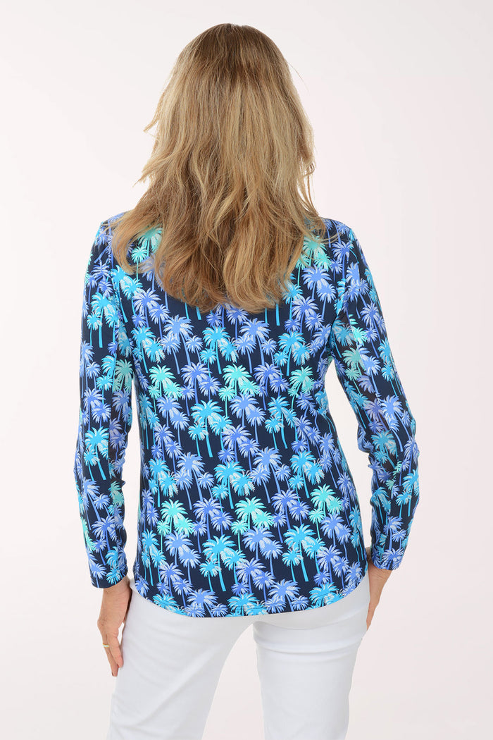 Woman wearing a blue palm tree patterned shirt on a white background