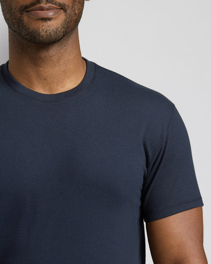 Man wearing a navy blue t-shirt against a neutral background