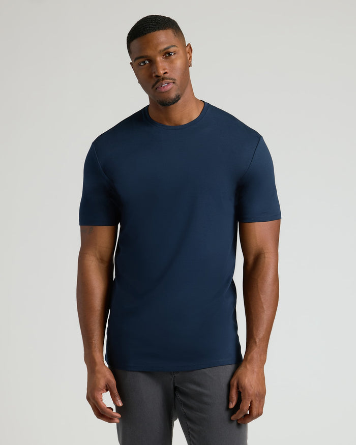 Male model wearing a navy blue Tall Pima Cotton Blend Crew 4-Pack T-shirt, showcasing a fitted, classic crew neck style for men's basics.
