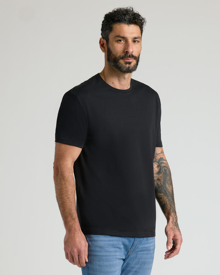 Man wearing a black Pima Cotton Blend Crew 4-Pack t-shirt paired with blue jeans, showcasing a comfortable and classic men's basics style.