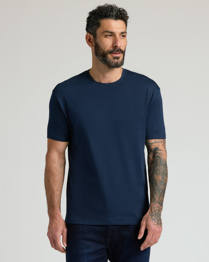 Man wearing a navy blue crew neck t-shirt from the Pima Cotton Blend Crew 4-Pack, paired with dark jeans, standing against a neutral background.