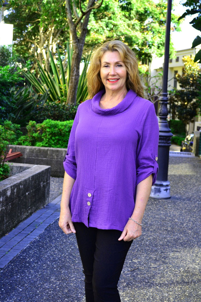 Purple rolled neck coconut button tunic top by Ruby Rain, featuring a relaxed fit and stylish design, displayed on a hanger.