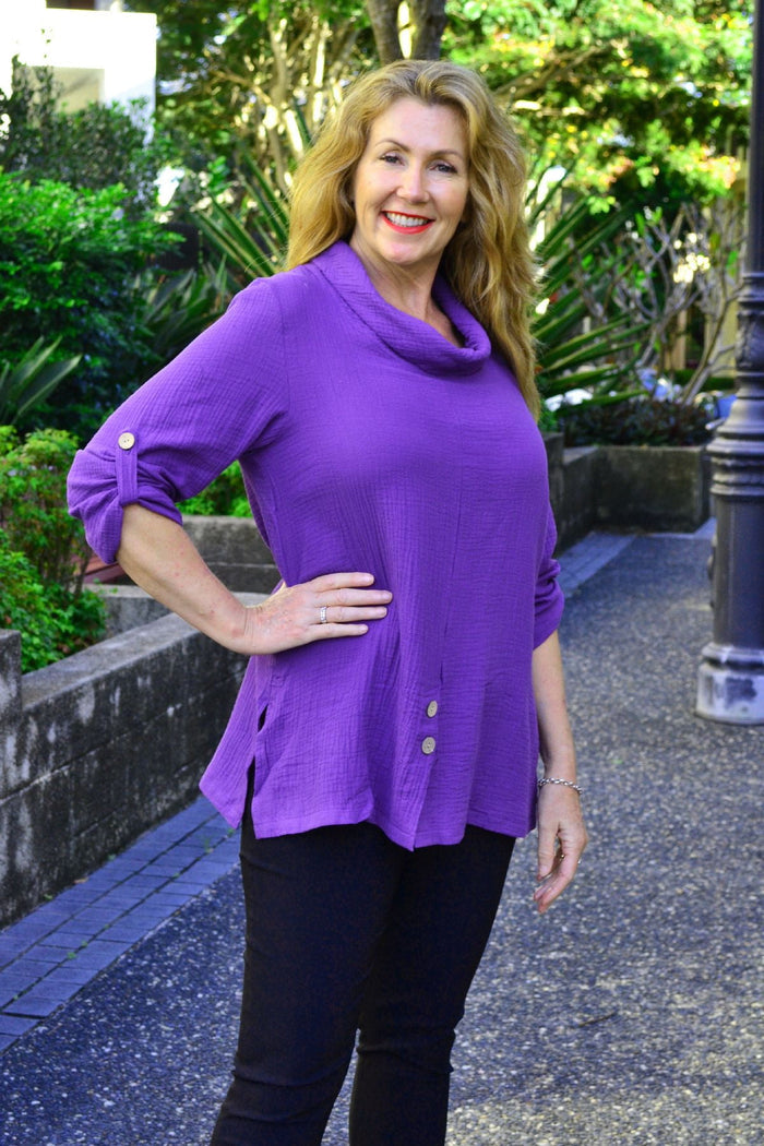 Purple rolled neck coconut button tunic top by Ruby Rain, featuring long sleeves and a relaxed fit, displayed on a hanger.