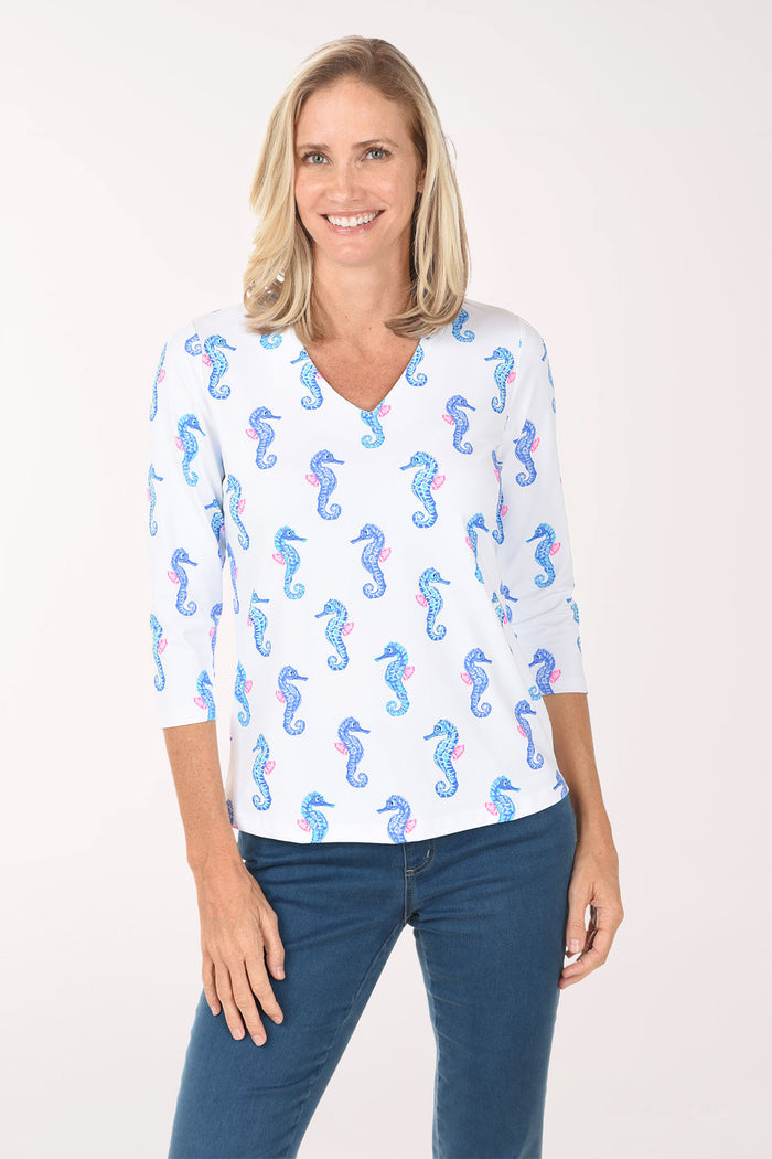 Woman wearing a white blouse with blue seahorse pattern on a white background