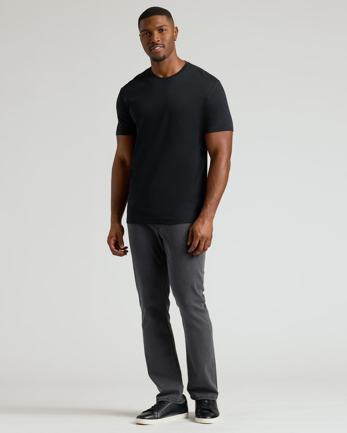 Man wearing a black crew neck t-shirt styled with gray pants and black sneakers, showcasing the Tall Pima Cotton Blend Crew 4-Pack as a comfortable men's basic essential.