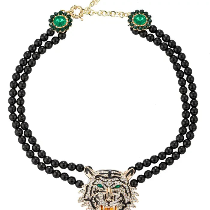 Double-strand black onyx statement necklace with a crystal pavé tiger head pendant, emerald green eye accents, and gold finish hardware.