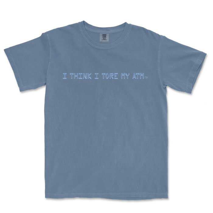 Blue T-shirt with the text "I THINK I TORE MY ATM." printed across the front in light blue font.