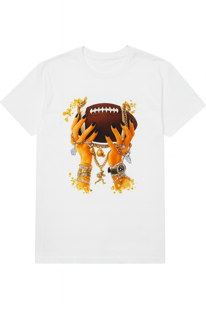 White short-sleeve graphic tee featuring jewelry-adorned hands with gold accents holding a football.