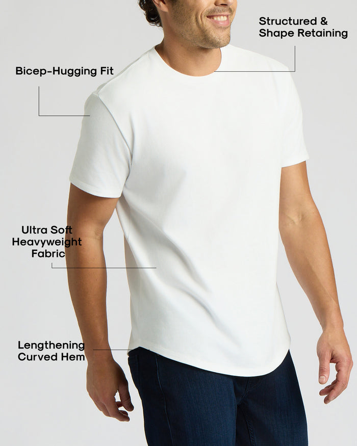 Man wearing an All White Heavyweight Curved Hem Crew 3-Pack shirt highlighting its bicep-hugging fit, structured shape, ultra-soft heavyweight fabric, and lengthening curved hem.