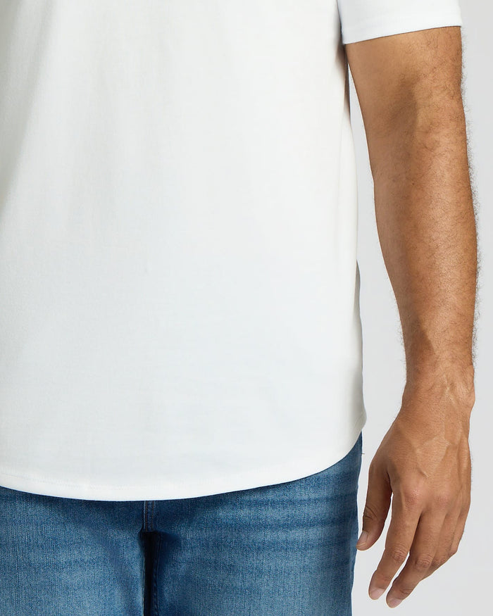 Close-up of a man wearing a white Tall Heavyweight Curved Hem Crew 3-Pack shirt paired with blue jeans, showcasing the curved hem detail on the men's basics staple.