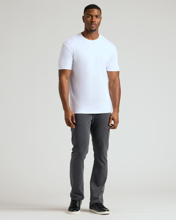 Man wearing a white Tall Pima Cotton Blend Crew 4-Pack t-shirt paired with dark gray pants and black sneakers, showcasing a clean and modern men's basics look.